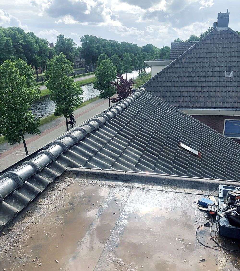 Nat plat dak naast een pannendak, tijdens het reinigen