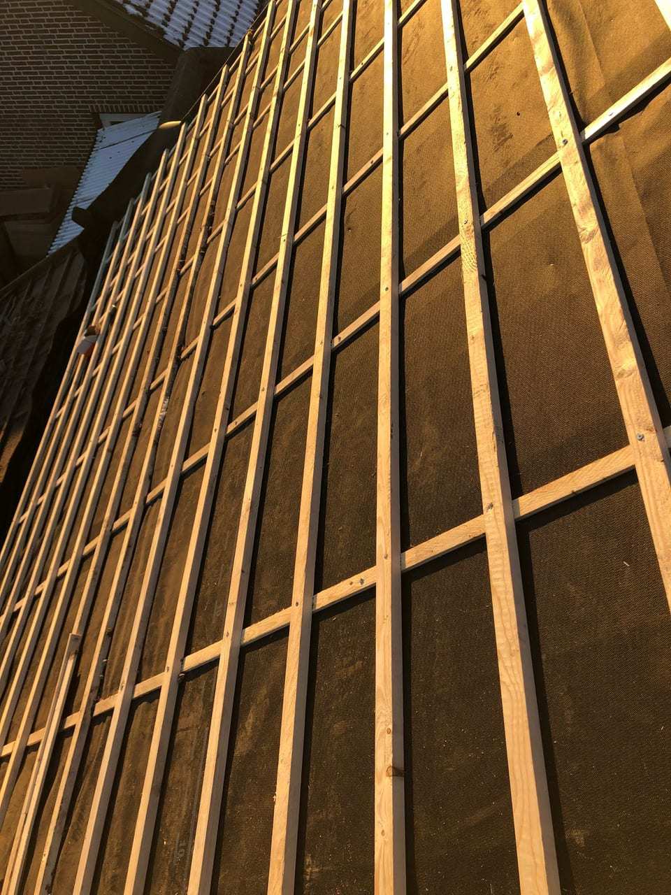 Nieuwe tengels en panlatten op een donkere dakfolie, in laag zonlicht